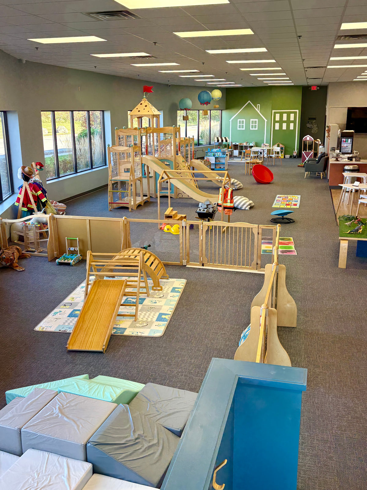 Inside Bug & Goose’s Delafield, Wisconsin play café, with wooden climbing structures, slides, toys, and adult seating.